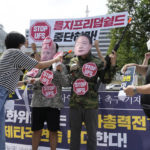 
              A protester puts a sticker on her fellow protesters wearing masks of U.S. President Joe Biden, left, and South Korean President Yoon Suk Yeol during a rally to oppose planned joint military exercises, called the Ulchi Freedom Shield, between South Korea and the United States on the occasion of U.S. House of Representatives Speaker Nancy Pelosi's visit in the South Korea, in front of the presidential office in Seoul, South Korea, Thursday, Aug. 4, 2022. The banner reads, "Stop the Ulchi Freedom Shield." (AP Photo/Ahn Young-joon)
            