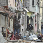 
              Police investigate the site of an explosion in the Cristo de El Consuelo neighborhood, in Guayaquil, Ecuador, Sunday, Aug. 14, 2022. According to the authorities a gunshot attack and subsequent explosion left at least five dead, 15 injured and several missing and affected homes. (AP Photo/ Magdalena Moreira)
            