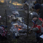 
              Gonzalo Rauque, 3, helps his mother, Constanza, rotate a rack of lamb during the multiday celebration of We Tripantu, the Mapuche new year, in the Corayen community of Los Rios, southern Chile, on Tuesday, June 21, 2022. (AP Photo/Rodrigo Abd)
            