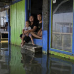 
              Jaka Sadewa, right, his wife Sri Wahyuni and son Bima pose for a photo in Timbulsloko, Central Java, Indonesia, Sunday, July 31, 2022. "I'm worried that every year the water will get higher. But we don't have any resources," she says. "If we had resources, we would move out." (AP Photo/Dita Alangkara)
            