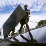 
              FILE - Employees of NY State Solar, a residential and commercial photovoltaic systems company, install an array of solar panels on a roof, Aug. 11, 2022, in the Long Island hamlet of Massapequa, N.Y. Massive incentives for clean energy in the U.S. law signed Tuesday, Aug. 16, by President Joe Biden should reduce future global warming “not a lot, but not insignificantly either,” according to a climate scientist who led an independent analysis of the climate package.  (AP Photo/John Minchillo, File)
            