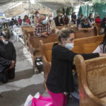 
              Devotees kneel in prayer during an outdoor Mass held under a tent just outside the quake-damaged Our Lady of the Angels Catholic church, in the Guerrero neighborhood of Mexico City, Sunday, Aug. 7, 2022. According to the National Institute of Anthropology and History, Our Lady of the Angels is the second most important temple in Mexico City after the internationally revered Basilica of Guadalupe. (AP Photo/Ginnette Riquelme)
            