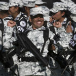 
              FILE - A National Guardsman smiles while stretching before the start of a presentation ceremony at a military field in Mexico City, June 30, 2019. The National Guard which includes federal police, marines, soldiers and new recruits was created to stem endemic violence and restore peace in the country. (AP Photo/Christian Palma, File)
            