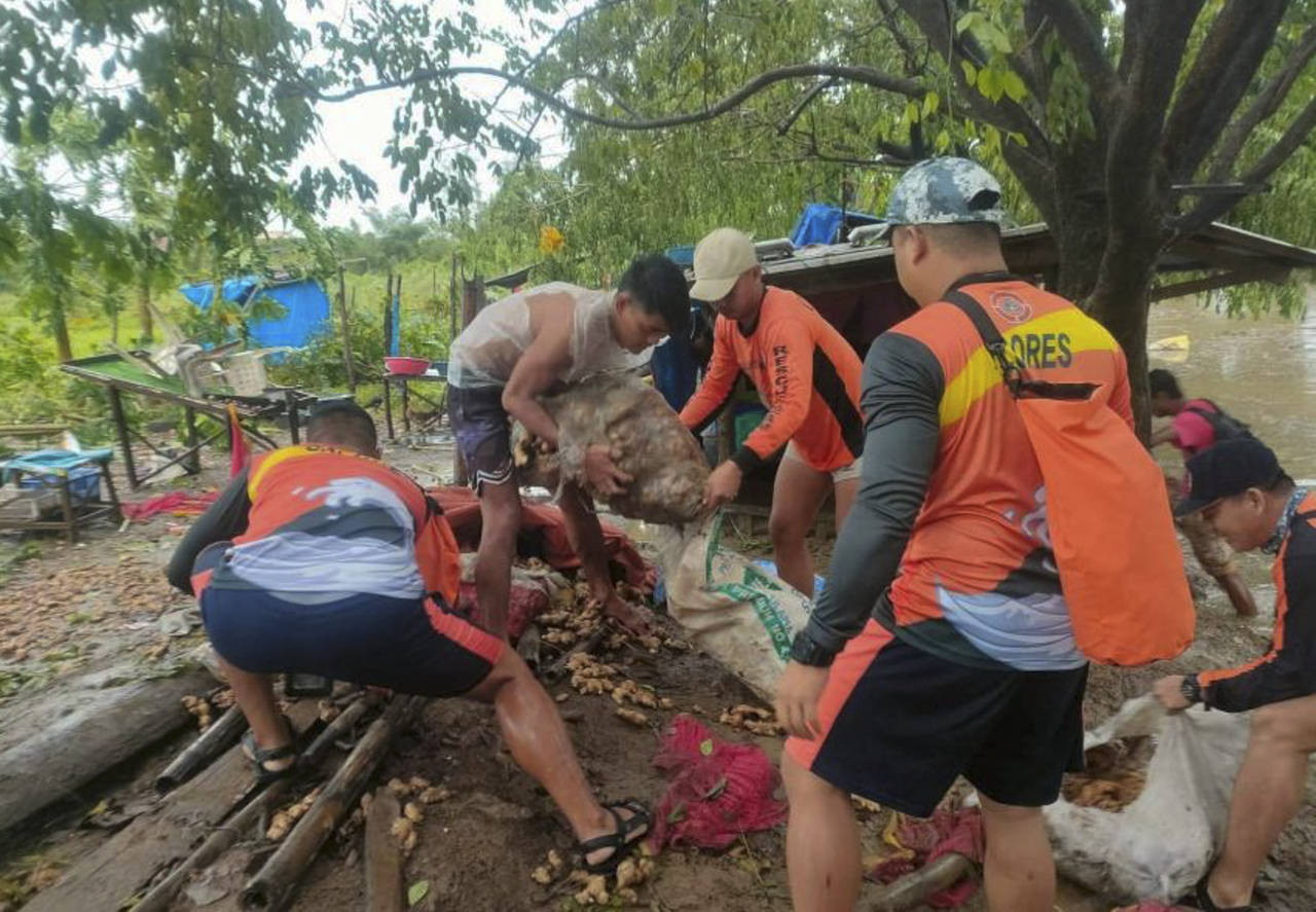 In this photo provided by the Philippine Coast Guard, rescuers carry vegetables as they move them t...