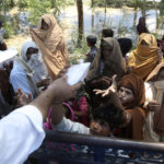 
              Displaced families receive food and take refuge on a roadside after fleeing their flood-hit homes, on the outskirts of Peshawar, Pakistan, Sunday, Aug. 28, 2022. Army troops are being deployed in Pakistan's flood affected area for urgent rescue and relief work as flash floods triggered after heavy monsoon rains across most part of the country lashed many districts in all four provinces. (AP Photo/Mohammad Sajjad)
            