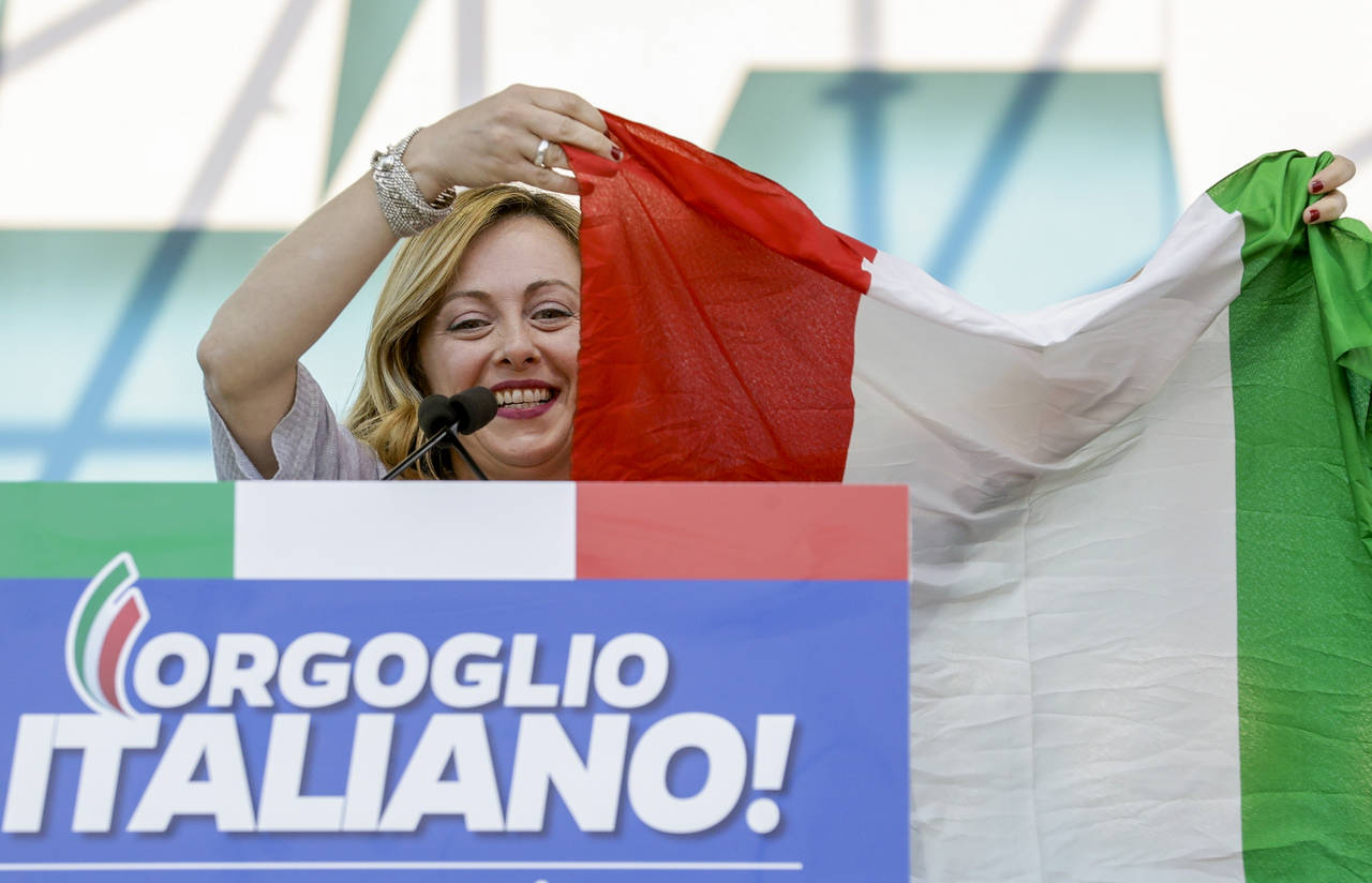 FILE — Giorgia Meloni holds an Italian flag as she addresses a rally in Rome, Saturday, Oct. 19, ...