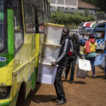 
              An electoral worker offloads ballot boxes from a minibus transporting electoral workers to a collection and tallying center in Nairobi, Kenya Wednesday, Aug. 10, 2022. Kenyans are waiting for the results of a close but calm presidential election in which the turnout was lower than usual. (AP Photo/Ben Curtis)
            