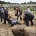 
              Workers put into a grave a coffin with unidentified remains of a civilian murdered by the Russian troops during Russian occupation in Bucha, on the outskirts of Kyiv, Ukraine, Thursday, Aug. 11, 2022. Eleven unidentified bodies exhumed from a mass grave were buried in Bucha Thursday. (AP Photo/Efrem Lukatsky)
            