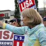
              U.S. Sen. Lisa Murkowski, an Alaska Republican, flashes a thumbs-up to a passing motorist while waving signs, Tuesday, Aug. 16, 2022, in Anchorage, Alaska. Murkowski faces 18 challengers in the state's open primary for U.S. Senate, in which the top four vote-getters regardless of party affiliation will advance to the November general election. (AP Photo/Mark Thiessen)
            