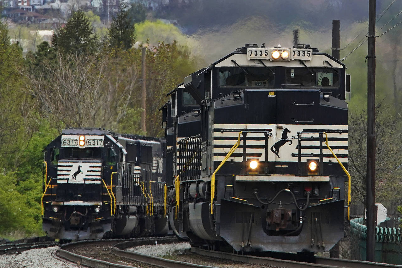 FILE - A Norfolk Southern freight train passes a train on a siding as it approaches a crossing in H...