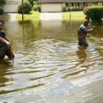 
              Hinds County Emergency Management Operations deputy director Tracy Funches, right, and operations coordinator Luke Chennault, wade through flood waters in northeast Jackson, Miss., Monday, Aug. 29, 2022, as they check water levels. Flooding affected a number neighborhoods that are near the Pearl River. (AP Photo/Rogelio V. Solis)
            