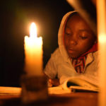 
              Tracy Carlos uses a candlelight to do her homework in Mabvuku on the outskirts of Harare on Wednesday, Aug, 3, 2022.Because of lengthy power cuts, the children do their homework by a candle, although their parents press them to use it sparingly. Her father Jeff Carlos says he gets about $100 dollars a month from his job as an overnight security guard for a church and the bar next door. Rising prices and a fast-depreciating currency have pushed many Zimbabweans to the brink, reminding people of when the southern African country faced world-record inflation of 5 billion % in 2008.(AP Photo/Tsvangirayi Mukwazhi)
            