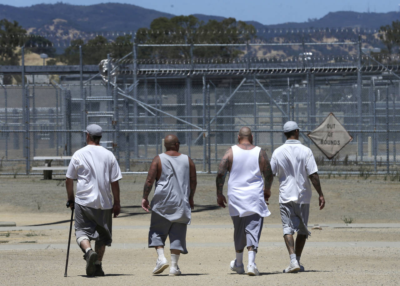 FILE - Inmates walk the exercise yard at the California Medical Facility in Vacaville, Calif., June...