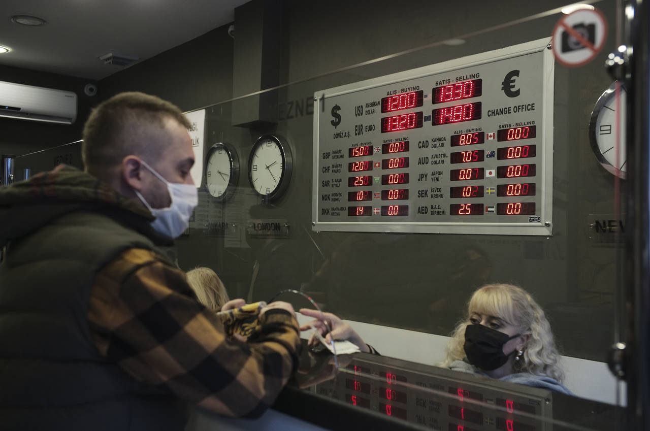 FILE - A man changes Turkish lira for USD and Euro at a currency exchange shop, in Ankara, Turkey, ...
