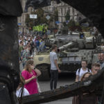 
              Ukrainians visit an avenue where destroyed Russian military technics have been displayed in Kyiv, Ukraine, Saturday, Aug. 20, 2022. Drawing the attention of large numbers of pedestrians and amateur snappers on Saturday in downtown Kyiv a large column of burned out and captured Russian tanks and infantry carriers is on display on the central Khreshchatyk boulevard. (AP Photo/Andrew Kravchenko)
            