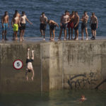 
              A group of young men cool off in the hot weather by diving into the water at Cullercoats Bay in North Tyneside, England, Wednesday Aug. 10, 2022. The Met Office has issued an amber warning for extreme heat covering four days from Thursday to Sunday for parts of England and Wales as a new heatwave looms. (Owen Humphreys/PA via AP)
            