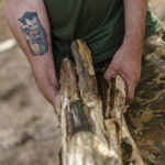 
              A tattoo of the "Joker" decorates the arm of a soldier with the Dnipro-1 regiment as he carries logs to fortify a position near Sloviansk, Donetsk region, eastern Ukraine, Friday, Aug. 5, 2022. While the lull in rocket strikes has offered a reprieve to remaining residents, some members of the Ukrainian military unit say it could be a prelude to renewed attacks. (AP Photo/David Goldman)
            