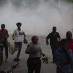 
              Protesters are dispersed by tear gas thrown by the police during a protest in Port-au-Prince, Haiti, Monday, Aug. 22, 2022. Protesters marched through Haiti's capital and other major cities, blocking roads and shutting down businesses to demand that Prime Minister Ariel Henry step down and call for a better quality of life. (AP Photo/Odelyn Joseph)
            