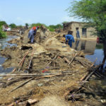 
              Pakistani men look for salvageable belongings from their flood-hit home surrounded by water, in Jaffarabad, a district of Pakistan's southwestern Baluchistan province, Sunday, Aug. 28, 2022. Army troops are being deployed in Pakistan's flood affected area for urgent rescue and relief work as flash floods triggered after heavy monsoon rains across most part of the country lashed many districts in all four provinces. (AP Photo/Zahid Hussain)
            