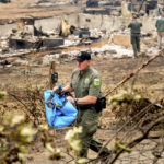 
              Sheriff's Deputy Johnson carries remains of a McKinney Fire victim from a destroyed home on Monday, Aug. 1, 2022, in Klamath National Forest, Calif. (AP Photo/Noah Berger)
            