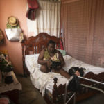 
              Duverseau Marie Cephta, whose leg was amputated when she was injured in last year's 7.2-magnitude earthquake, listens to news via a radio inside her home in the Lagodray area of Les Cayes, Haiti, Friday, Aug. 19, 2022. (AP Photo/Odelyn Joseph)
            