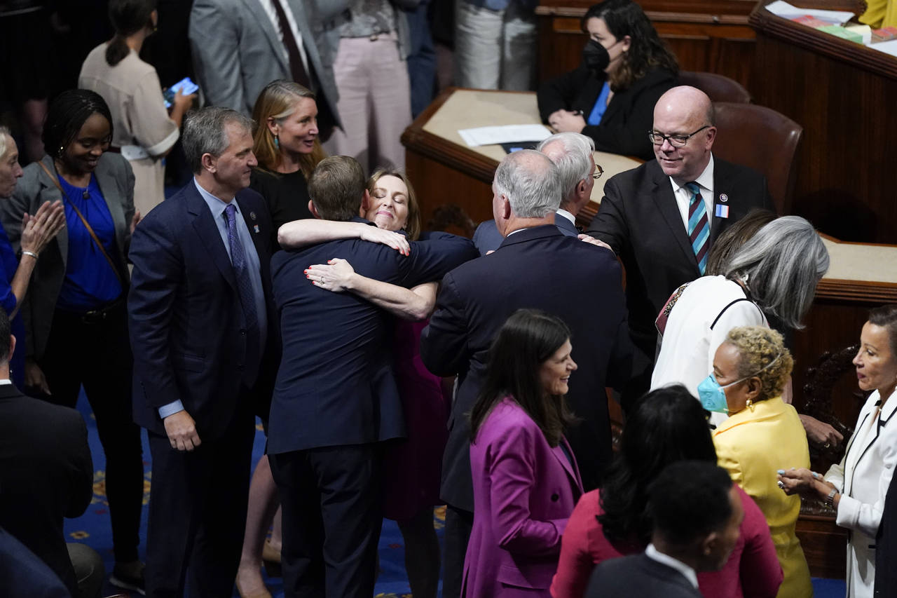 Members of the House of Representatives gather in the chamber to celebrate after the vote to approv...