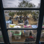 
              An electoral worker stands with ballot boxes lined up and ready to be stored at a collection and tallying center in Nairobi, Kenya Wednesday, Aug. 10, 2022. Kenyans are waiting for the results of a close but calm presidential election in which the turnout was lower than usual. (AP Photo/Ben Curtis)
            