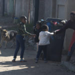 
              A woman pulls children off a street as local residents comb the neighbourhood in search of illegal miners in West Village, Krugersdorp, South Africa Friday Aug. 5, 2022. Community members converged on the neighbourhood in search of illegal miners following the alleged gang rapes of eight women by miners last week. (AP Photo/Denis Farrell)
            