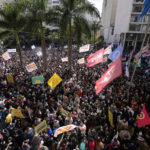 
              People gather the reading of one of two manifestos defending the nation's democratic institutions and electronic voting system outside the Faculty of Law at Sao Paulo University in Sao Paulo, Brazil, Thursday, Aug. 11, 2022. The two documents are inspired by the original “Letter to the Brazilians” from 1977 denouncing the brutal military dictatorship and calling for a prompt return of the rule of law. (AP Photo/Andre Penner)
            