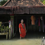 
              Zuriah stands outside her flooded home in Mondoliko, Central Java, Indonesia, Monday, Aug. 1, 2022. Unable to afford to move to a new home, Zuriah continues to live in the house even as nearly all of her neighbors move away. (AP Photo/Dita Alangkara)
            