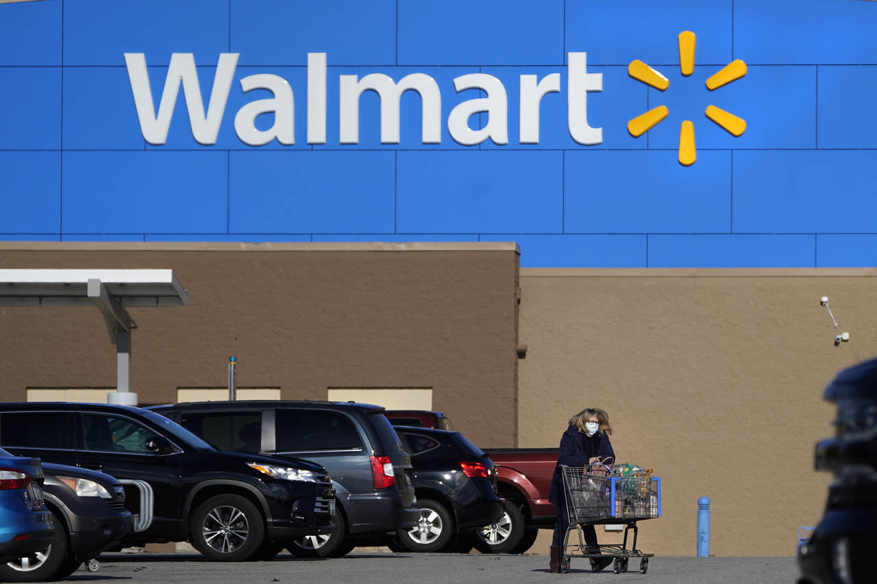 FILE - A woman wheels a cart with her purchases out of a Walmart, on Nov. 18, 2020, in Derry, N.H. ...