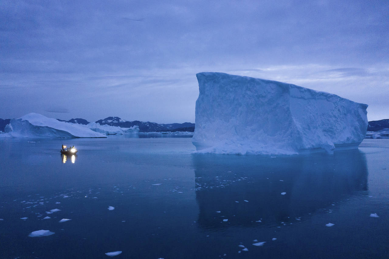 FILE - A boat navigates at night next to large icebergs in eastern Greenland on Aug. 15, 2019. Zomb...