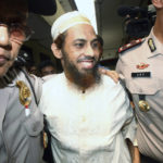 
              FILE - Terrorist suspect Umar Patek, center, is escorted by police officers as he arrives to testify for his wife, Ruqayyah binti Husein Luceno, who is on trial for immigration violations, at a district court in Jakarta, Indonesia, Monday, Nov. 29, 2011. 
Australian Prime Minister Anthony Albanese said Friday, Aug. 19, 2022, that it's upsetting Indonesia has further reduced the prison sentence of the bombmaker Patek in the Bali terror attack that killed 202 people — meaning the terrorist could be freed within days if he's granted parole. (AP Photo/Tatan Syuflana, File)
            