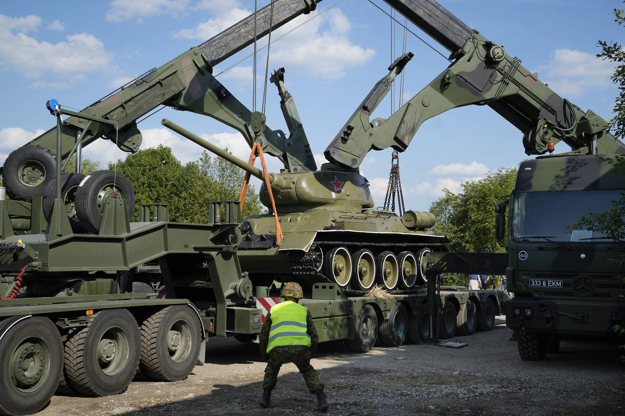 Cranes unload a Soviet T-34 tank which was installed as a monument in Narva from a trailer at a mil...