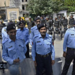 
              Pakistani police officers and paramilitary soldiers stand guard outside the head office of Pakistan's election commission, in Islamabad, Pakistan, Tuesday, Aug. 2, 2022. Pakistan's elections oversight body ruled Tuesday that former Prime Minister Imran Khan accepted illegal donations to his political party from abroad. It's a key first step toward a possible ban on Khan and his party from politics. (AP Photo/W.K. Yousufzai)
            