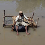 
              A displaced man carries belongings he salvaged from his flood-hit home as he paddles through a flooded area, on the outskirts of Peshawar, Pakistan, Sunday, Aug. 28, 2022. Army troops are being deployed in Pakistan's flood affected area for urgent rescue and relief work as flash floods triggered after heavy monsoon rains across most part of the country lashed many districts in all four provinces. (AP Photo/Mohammad Sajjad)
            