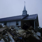 
              Piles of debris sit near a church after massive flooding on Friday, Aug. 5, 2022, in Lost Creek, Ky.  As residents continued cleaning up from the late July floods that several people, rain started falling on already saturated ground in eastern Kentucky late Friday morning.  (AP Photo/Brynn Anderson)
            