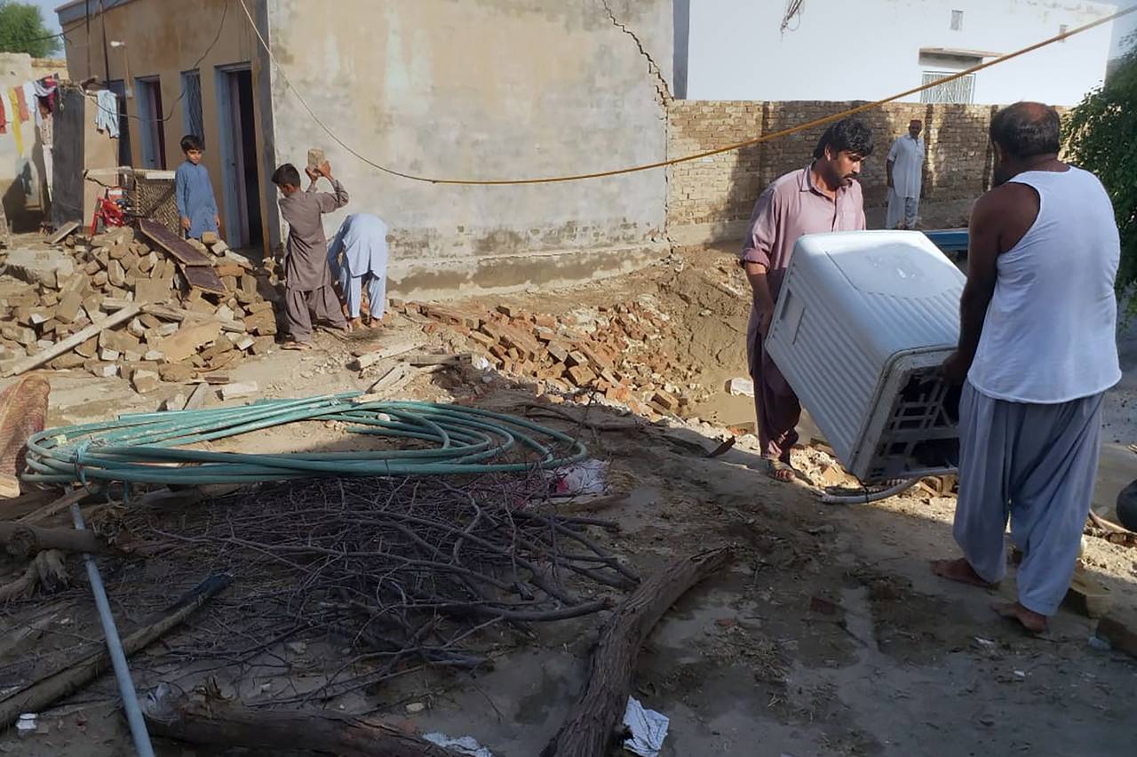 People salvage usable items from their house, which partially collapsed due to heavy rains, in Taun...