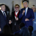 
              President Joe Biden speaks as David Furnish, husband of Elton John, left, Elton John and first lady Jill Biden listen after Biden presented him with a National Humanities Medal after a concert on the South Lawn of the White House in Washington, Friday, Sept. 23, 2022. (AP Photo/Susan Walsh)
            
