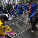 
              Student activists knock down a police razor wire barricade during a rally against sharp increases in fuel prices, in Jakarta, Indonesia, Thursday, Sept. 8, 2022. Hundreds of students rallied in Indonesia's capital on Thursday to protest sharp increases in fuel prices by the government. (AP Photo/Achmad Ibrahim)
            