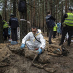 
              EDS NOTE: GRAPHIC CONTENT - An expert examines a body during an exhumation in the recently retaken area of Izium, Ukraine, Friday, Sept. 16, 2022. Ukrainian authorities discovered a mass burial site near the recaptured city of Izium that contained hundreds of graves. It was not clear who was buried in many of the plots or how all of them died, though witnesses and a Ukrainian investigator said some were shot and others were killed by artillery fire, mines or airstrikes. (AP Photo/Evgeniy Maloletka)
            