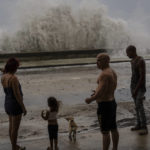 
              People stand along a waterfront as huge waves crash against a seawall in the wake of Hurricane Ian in Havana, Cuba, Wednesday, Sept. 28, 2022. Cuba remained in the dark early Wednesday after Ian knocked out its power grid and devastated some of the country's most important tobacco farms when it hit the island's western tip as a major storm. (AP Photo/Ramon Espinosa)
            