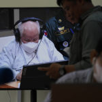 
              Khieu Samphan, former Khmer Rouge head of state, is seen on screen at the court's press center during a hearing at the U.N.-backed war crimes tribunal in Phnom Penh, Cambodia, Thursday, Sept. 22, 2022. The tribunal will issue its ruling on an appeal by Khieu Samphan, the last surviving leader of the Khmer Rouge government that ruled Cambodia from 1975-79. He was convicted in 2018 of genocide, crimes against humanity and war crimes and sentenced to life in prison. (AP Photo/Heng Sinith)
            
