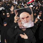 
              File - A pro-government demonstrator holds a poster of the late Iranian revolutionary founder Ayatollah Khomeini while attending a rally after the Friday prayers to condemn recent anti-government protests over the death of a young woman in police custody, in Tehran, Iran, Friday, Sept. 23, 2022. The crisis unfolding in Iran began as a public outpouring over the the death of Mahsa Amini, a young woman from a northwestern Kurdish town who was arrested by the country's morality police in Tehran last week for allegedly violating its strictly-enforced dress code. (AP Photo/Vahid Salemi, File)
            
