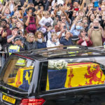 
              The hearse carrying the coffin of Queen Elizabeth II, draped with the Royal Standard of Scotland, passes the City Chambers on the Royal Mile, Edinburgh, Sunday, Sept. 11, 2022 on the journey from Balmoral to the Palace of Holyroodhouse in Edinburgh, where it will lie in rest for a day. (Jane Barlow/Pool Photo via AP)
            