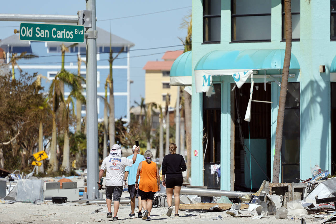 Island residents walk around the downtown area on the island of Fort Myers Beach, Fla., Friday, Sep...