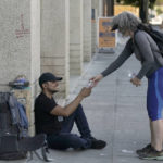 
              Freddie Ramirez, left, is handed a bottle of water from Kim Burrell, in Sacramento, Calif., Tuesday, Sept. 6, 2022. Burrell and Debbie Chang, unseen, passed out water and snacks to those they find in need on the streets. Temperatures in the Sacramento area are forecasted to reach record highs Tuesday. (AP Photo/Rich Pedroncelli)
            