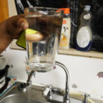 
              Sharon Epps, who lives in a rental home in the Queens neighborhood of Jackson, Miss., holds a glass of tap water taken from her kitchen faucet, Aug. 17, 2022. Even when Jackson is not under a boil-water notice, Epps said she buys bottled water for her family because she doesn't trust that the water coming out of the tap is safe to drink. (AP Photo/Rogelio V. Solis)
            