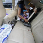 
              Shantia Crumb straps her daughter Jayda into her car seat after receiving two cases of water at a community drive-thru water distribution site in south Jackson, Miss., Sept. 7, 2022.  A boil-water advisory has been lifted for Mississippi's capital, and the state will stop handing out free bottled water on Saturday. But the crisis isn't over. Water pressure still hasn't been fully restored in Jackson, and some residents say their tap water still comes out looking dirty and smelling like sewage. (AP Photo/Rogelio V. Solis)
            