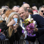 
              Britain's William, Prince of Wales poses for a photo with a well-wisher as he and Kate, Princess of Wales view floral tributes left by members of the public, in memory of late Queen Elizabeth II, at the Sandringham Estate, in Norfolk, England, Thursday, Sept. 15, 2022.  Queen Elizabeth II, Britain's longest-reigning monarch died Thursday Sept. 8, 2022, after 70 years on the throne. (Toby Melville/Pool via AP)
            